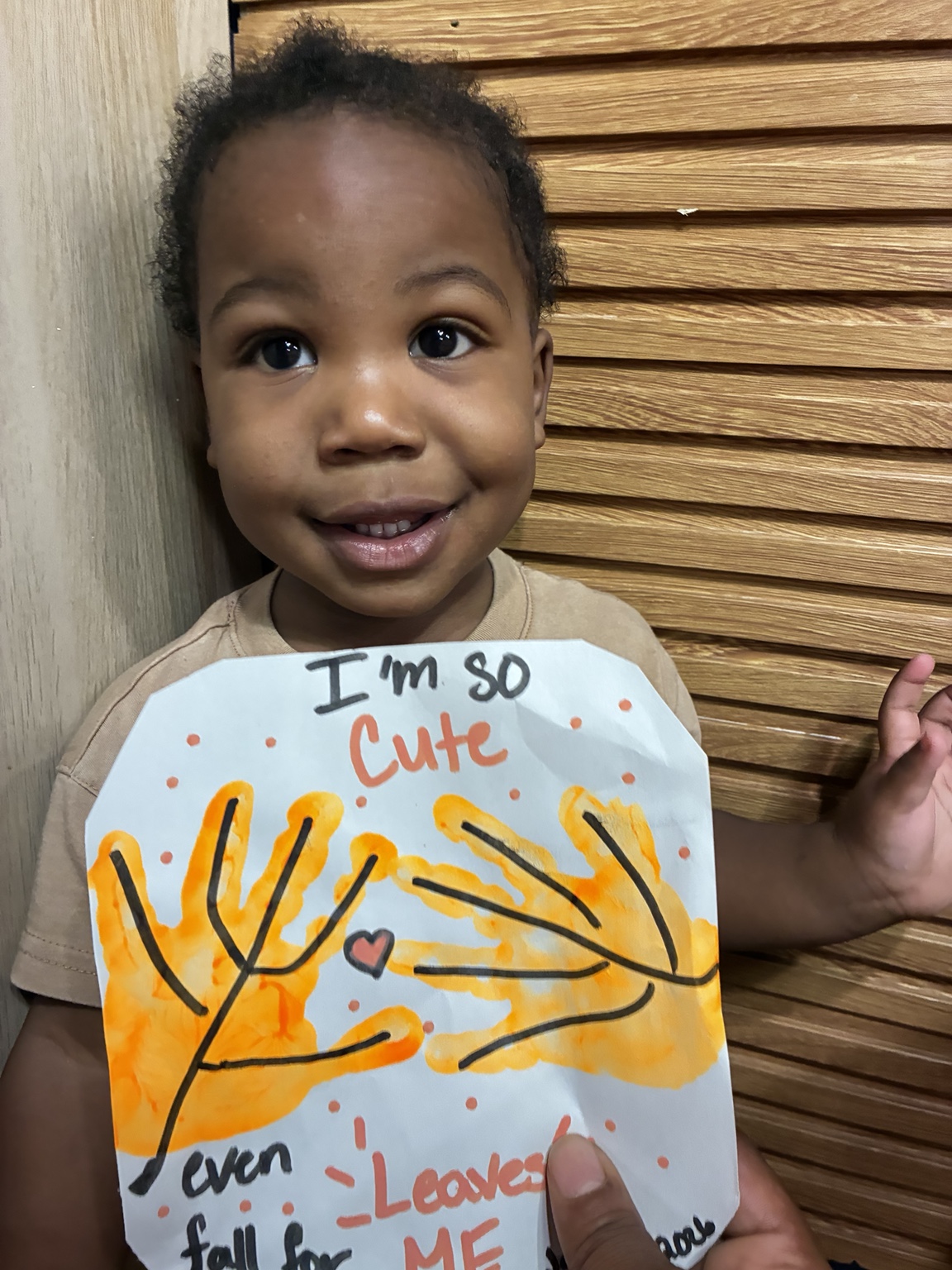 Child smiling with an autumn handprint craft